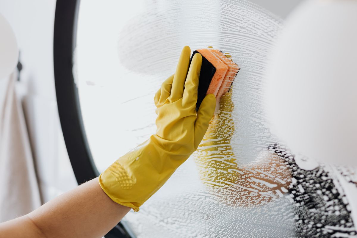 Fensterreinigung mit Schwamm und Gummihandschuh