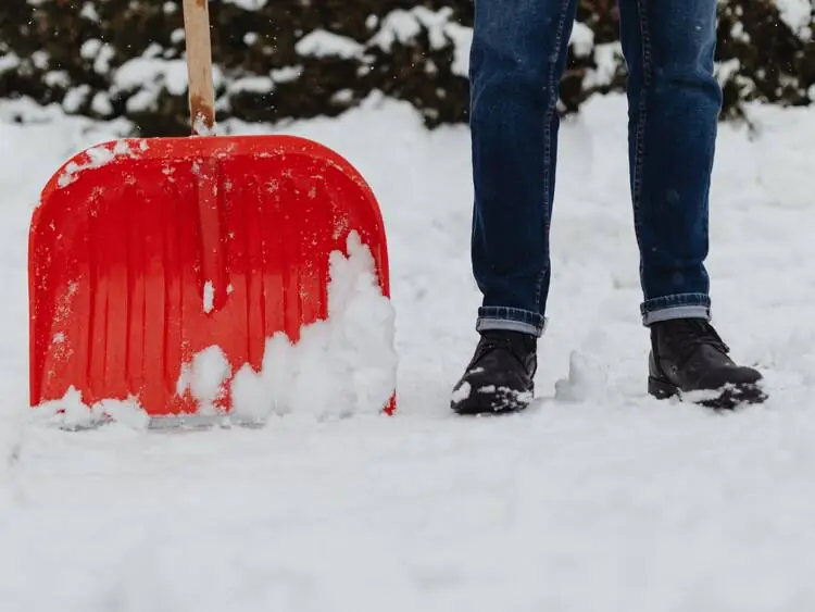 Schneeräumung mit rotem Schneeschieber